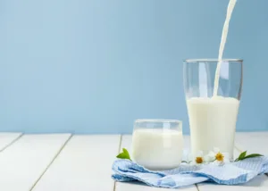 Glasses of milk on a blue cloth, representing dairy processing and the enzymatic use of lactase for lactose-free or lactose-reduced milk products