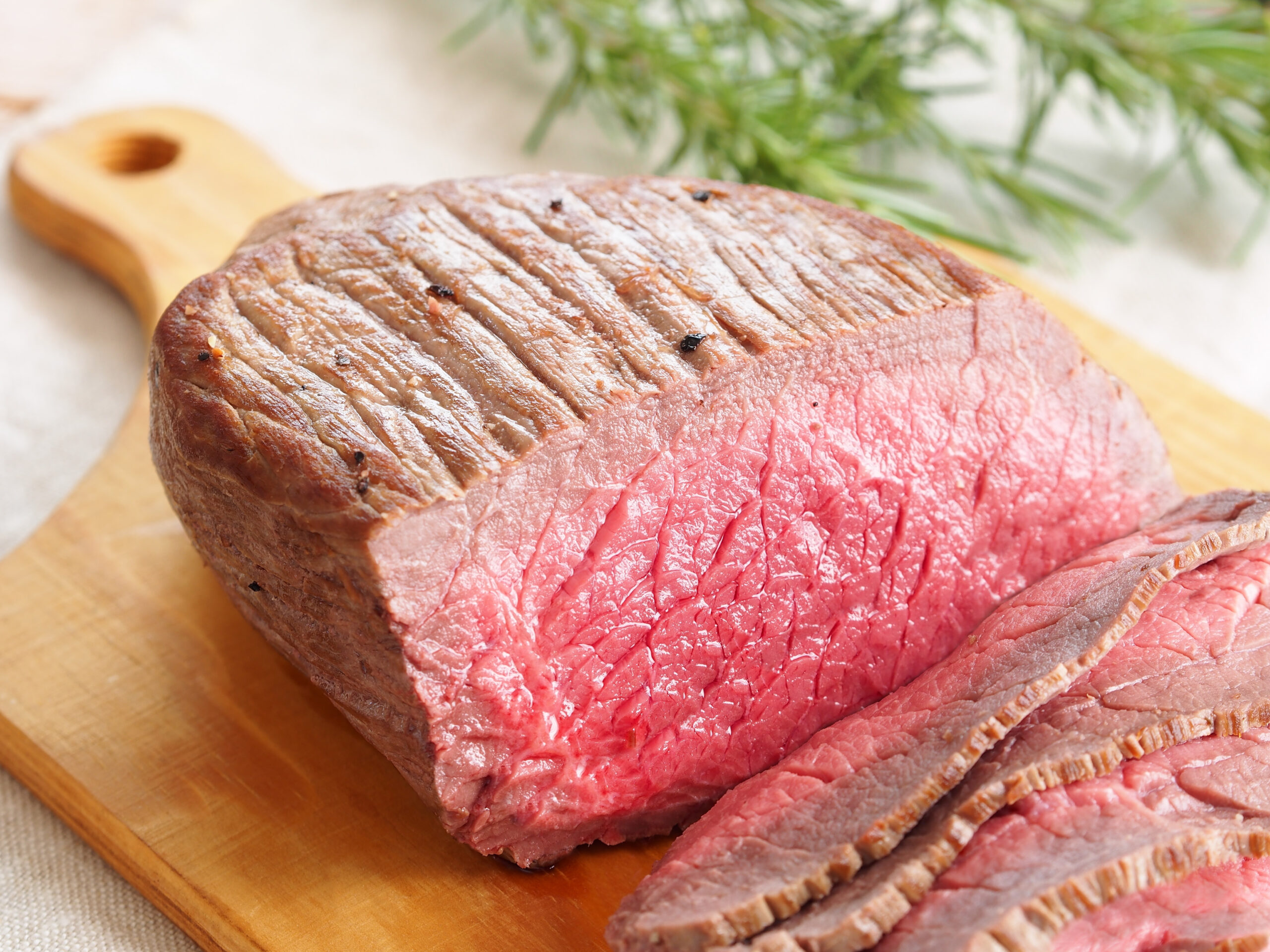 Cooked roast beef on a wooden board, illustrating the use of proteases in meat processing for improved tenderness and protein modification