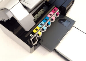 Close-up of an inkjet printer with six color cartridges (black, yellow, cyan, light cyan, magenta, light magenta) exposed—illustrating the role of Charge Control Agents in high-precision color management for advanced printing applications by Nagase.
