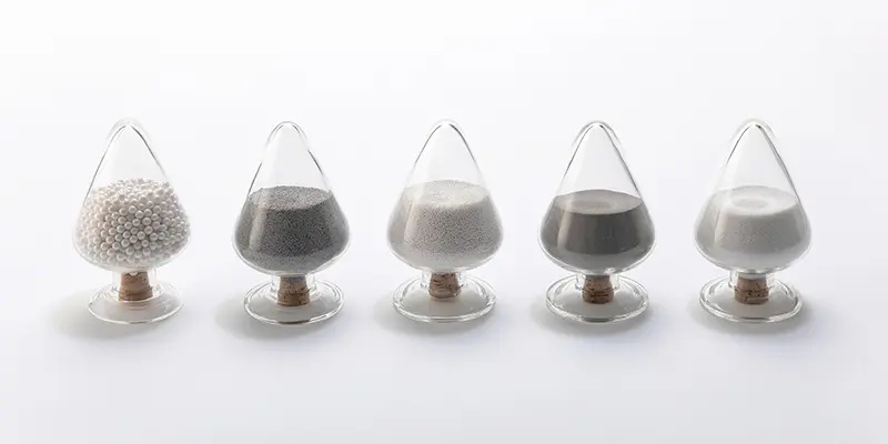 Selection of YTZP grinding media in various grain sizes and forms, displayed in glass sample containers for high-performance milling applications. Selection of YTZP grinding media in various grain sizes and forms, displayed in glass sample containers for high-performance milling applications.
