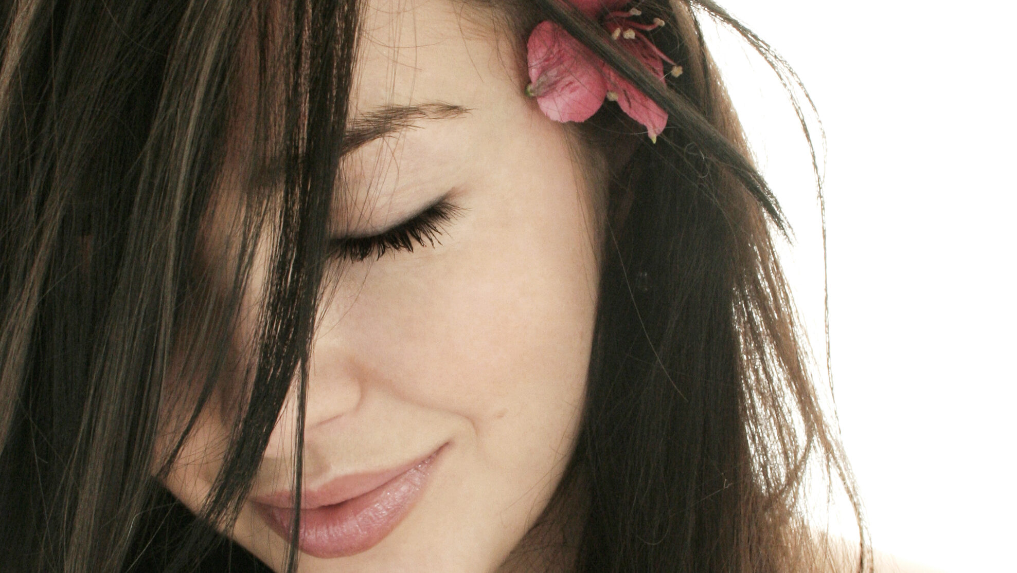 Woman with smooth, shiny hair and a pink flower, illustrating the natural moisturizing, smoothing, and shine-enhancing benefits of AngelRing® Funori seaweed hair care ingredient.