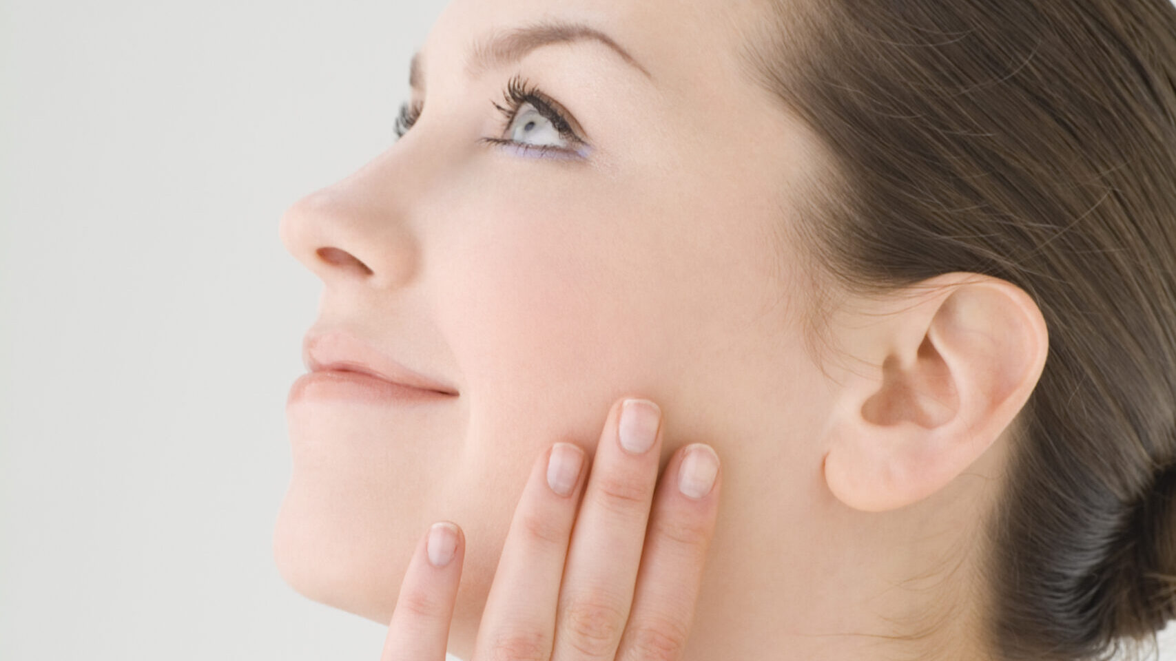 Woman touching her cheek with smooth, healthy-looking skin – illustrating anti-aging, wrinkle reduction, hydration, and skin barrier benefits of Pentadecyl®, a natural microalgae-derived cosmetic ingredient.