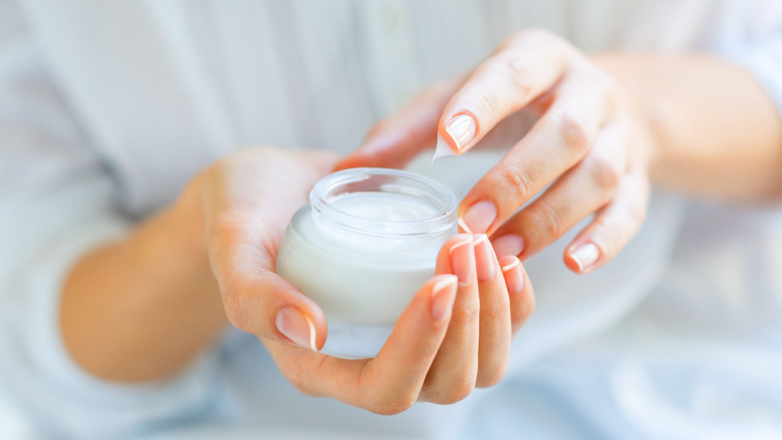 Hands applying a cosmetic cream from a jar, representing the moisturizing, soft-focus texture and natural clean-beauty performance of BIODIOS™ Liquid 100 glucomannan texturizer.