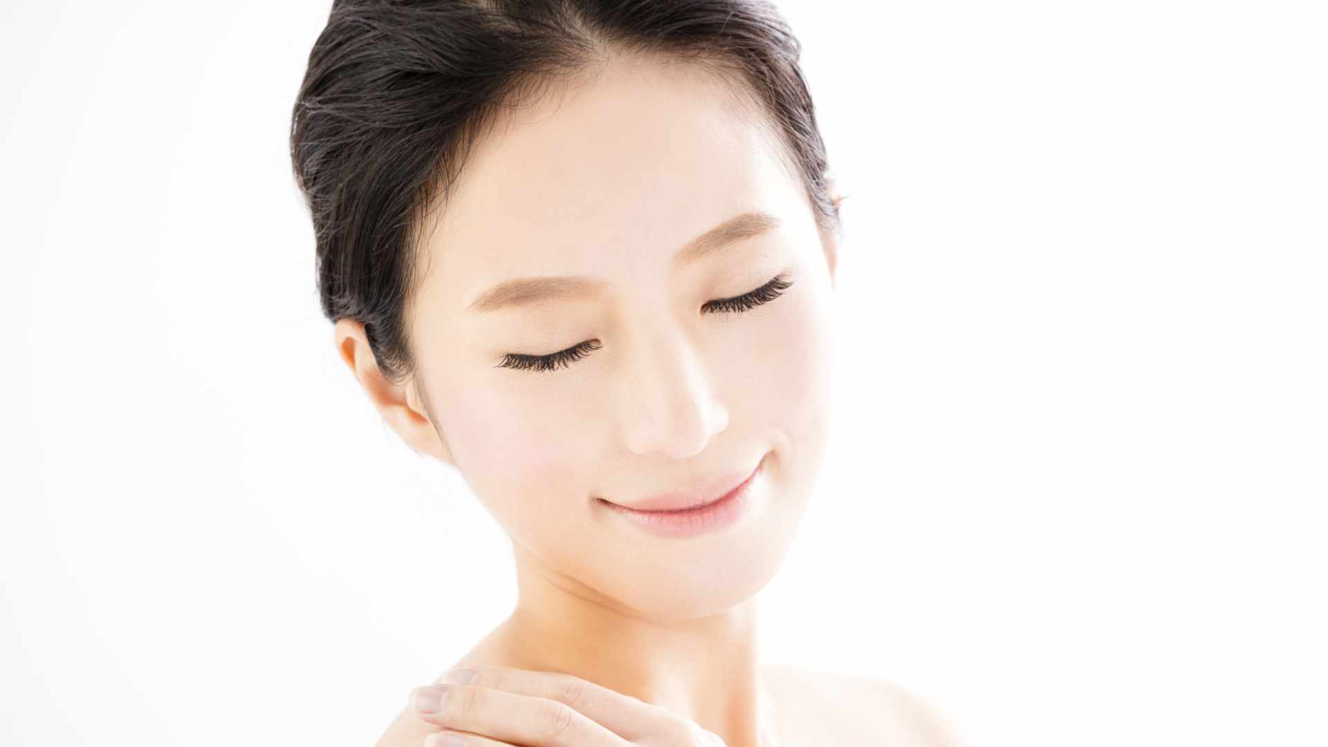 Woman with smooth, hydrated skin softly touching her shoulder, representing the moisturizing, barrier-strengthening, and anti-aging benefits of Rice Ceramide.